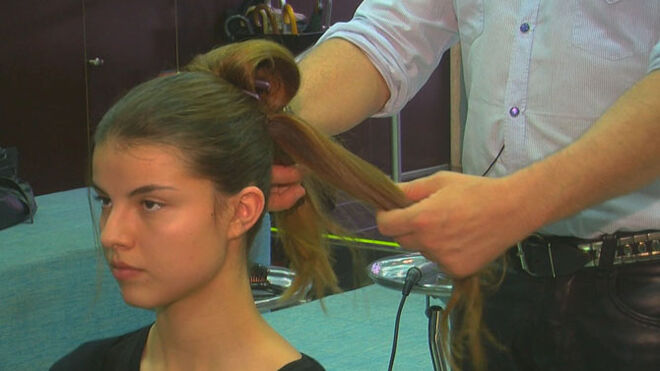 Dividir o rabo de cavalo em duas partes. Uma é presa em cima com um gancho enquanto trabalhamos a parte do cabelo caída