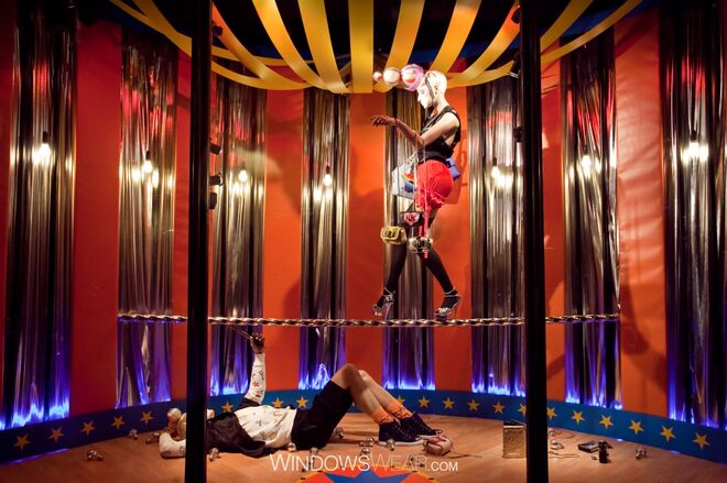 Londres | Harvey Nichols -  Estrelas, riscas e uma demostração de agilidade numa corda em saltos enquanto equilibra várias malas de mão para adicionar um elemento de surpresa e perigo nesta montra/vitrine Harvey Nichols.