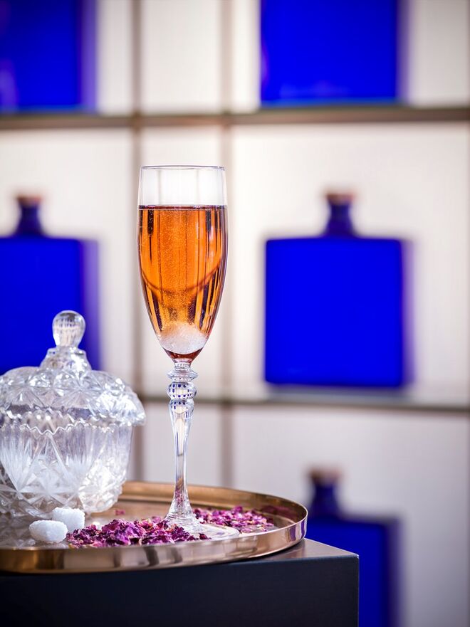 Para Ela: Haig Club Sunset | 4 cl de Haig Club; 1 cl de licro Creme de Cassis; 6 gotas de àgua de rosas; ½ cubo de açucar; Top de champanhe rosé. Para decoração: pétala de rosa (fresca ou desidratada)