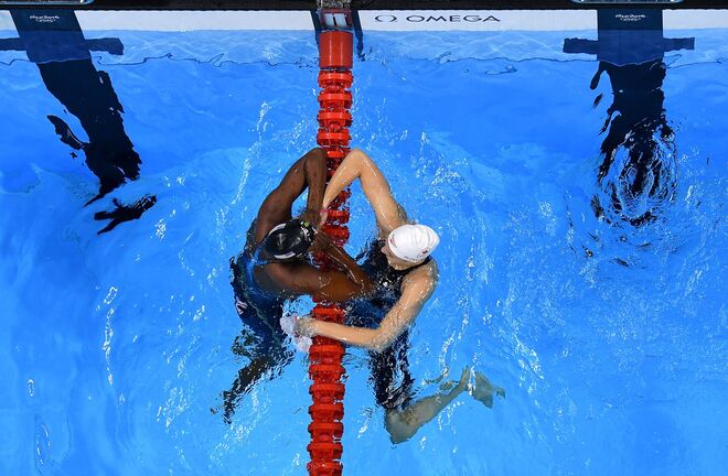 A americana Simone Manuel a abraçar a canadense Penny Oleksiak depois de ganhar o ouro nos 100m Freestyle | Natação