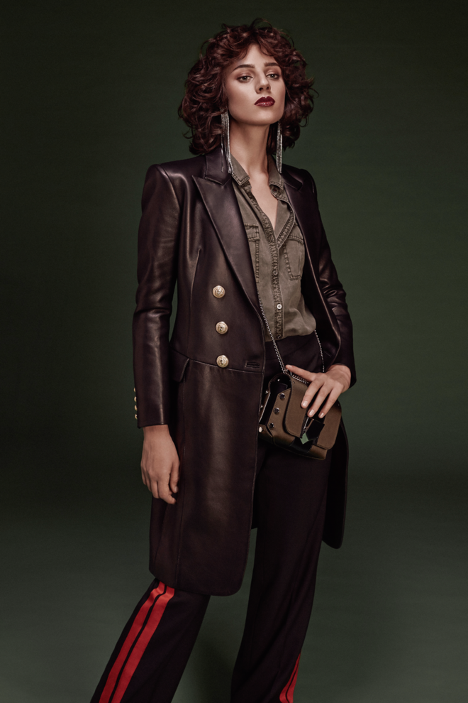 8. Peças distintas mostram que é possível brilhar em simultâneo sem perder o protagonismo: um imponente casaco militar, umas descontraídas calças desportivas e acessórios impactantes harmonizam-se com personalidade. | Casaco em pele, €4025, Balmain, na Fashion Clinic. Camisa em algodão, Hilfiger Denim (preço sob consulta). Calças em poliéster, €49,95, botas em pele, €79,99, e brincos em metal e vidro, €12,99, Zara. Carteira em pele e cetim, €1395, Jimmy Choo.