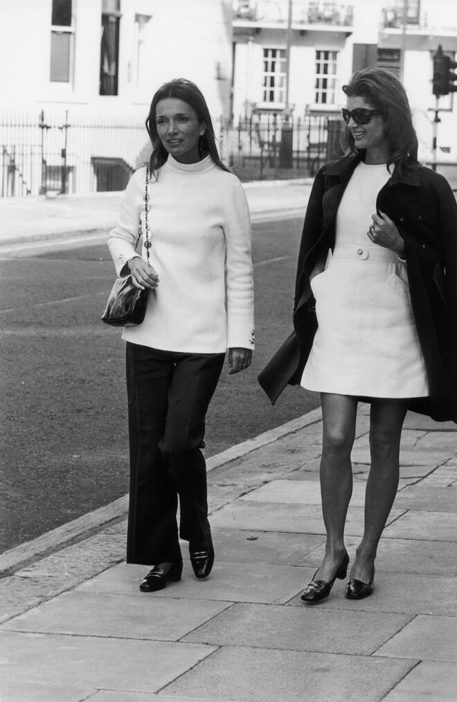 As irmãs Jackie Kennedy Onassis e Lee Radziwill em Londres, e outubro de 1970. Jackie usa um vestido trapézio minissaia e os seus característicos grandes óculos de sol.
