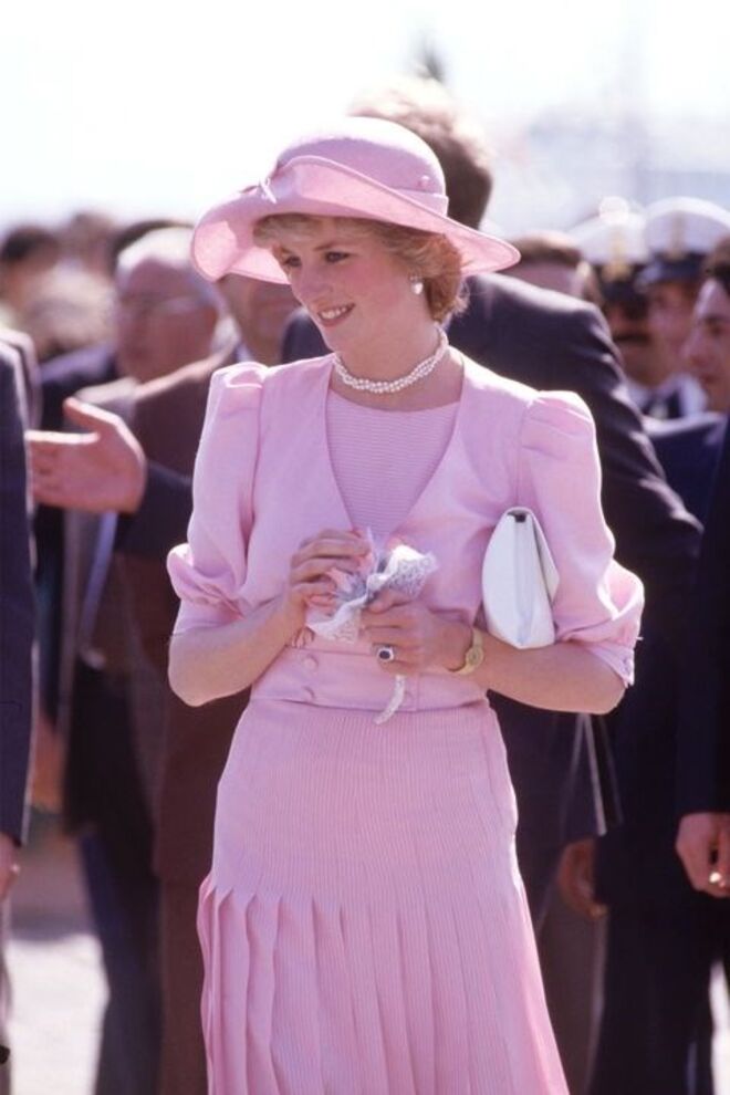 30 de abril 1985 | Com um vestido rosa claro de Catherine Walker e um chapéu desenhado por John Boyd, na chegada à Sicília.