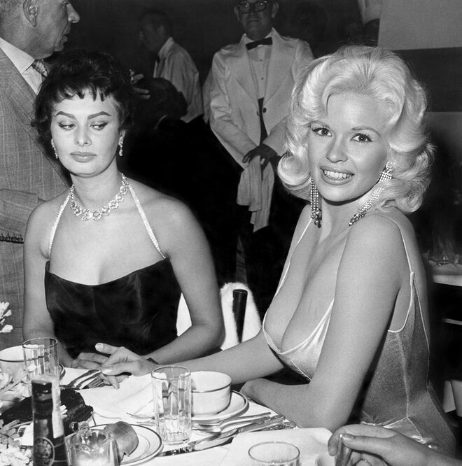 JAYNE MANSFIELD | Aquela que é provavelmente uma das fotografias mais famosas do mundo apanhou a atriz Sophia Loren a lançar um olhar desaprovador ao generoso decote de Jayne Mansfield, em 1957.