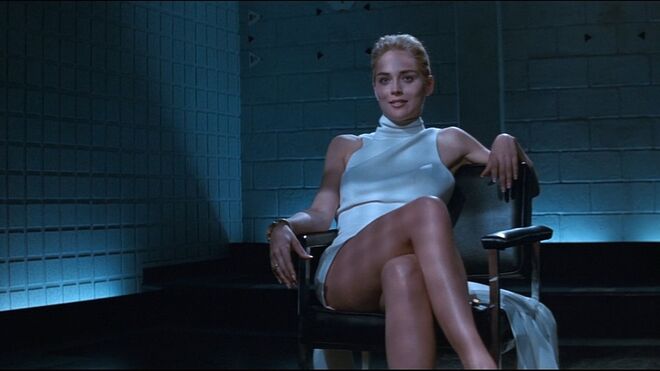 SHARON STONE | Em Instinto Fatal, Sharon Stone usa um vestido branco de gola alta quando cruza as pernas de forma sensual durante um interrogatório. O vestido ficou associado a uma das cenas mais icónicas do cinema.