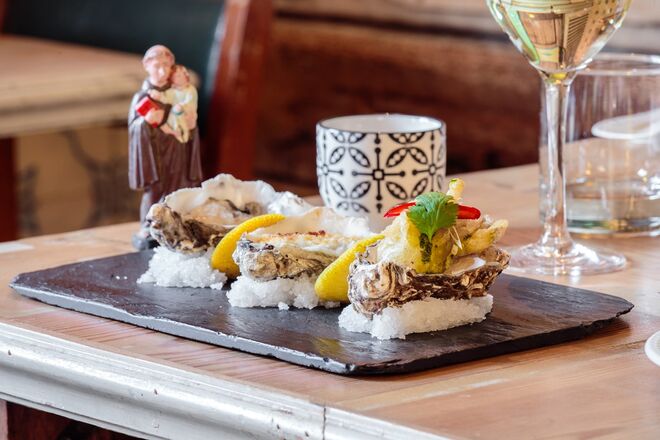 THE INSÓLITO | O menu de fim de ano do The Insólito começa com três tipos de ostras (frita em massa de cerveja, gratinada com queijo da ilha e panko ou ao natural), crepes de perna de pato confitada, pepino, cebolinho e molho hoisin, sapateira servida em pão de Mafra torrado e barrado com aioli, creme de alho-francês e ovas de lumpo ao natural. Para pratos principais há filete de robalo do mar, puré de topinambur, favas e castanhas defumadas e manteiga noisette (peixe) e lagartos de porco ibérico e seu jus, esmagada de abóbora manteiga com noz torrada e salsa, folha de mostarda e vinagrete de Dijon (carne). Há ainda uma opção vegetariana: torta de funcho gratinada com queijo da ilha e grelos salteados. As sobremesas serão sorbet de maçã verde com vodka grey goose gelada, pera rocha confitada em calda de especiarias e creme de cardamomo queimado. O preço, de €130 por pessoa, inclui o espumante e bar aberto até às 02h00.