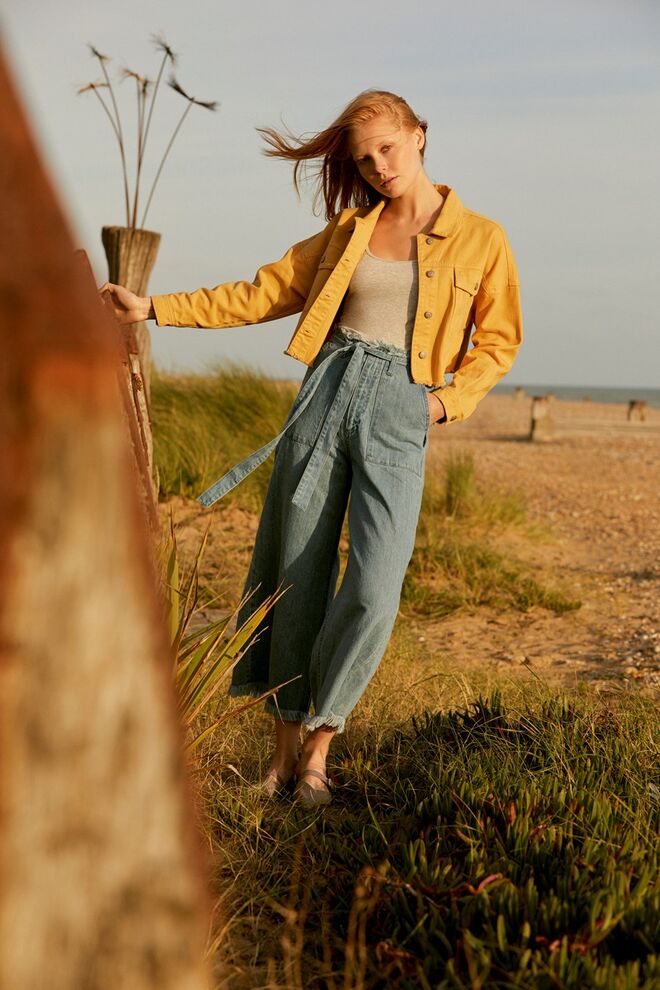 Jaqueta amarela (€19), T–Shirt (€3), calças de ganga (€19), sapato (€10), tudo Primark.