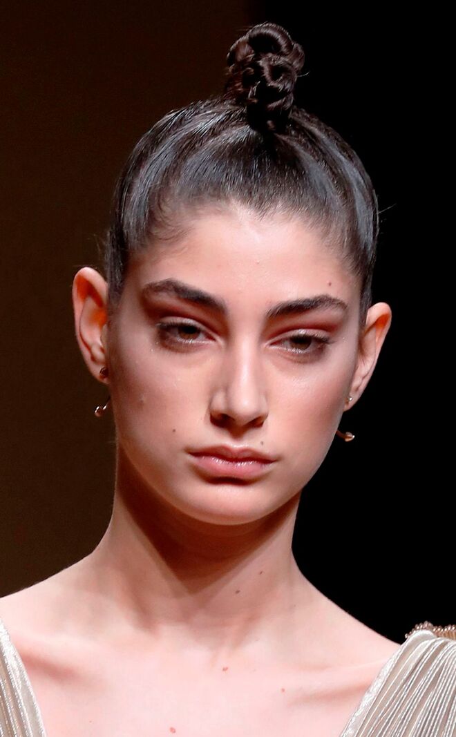 Desfile alta-costura primavera/verão 2018 Antonio Grimaldi: As modelos usaram o cabelo repuxado para cima e preso num coque alto e com pequenos gomos enrolados.