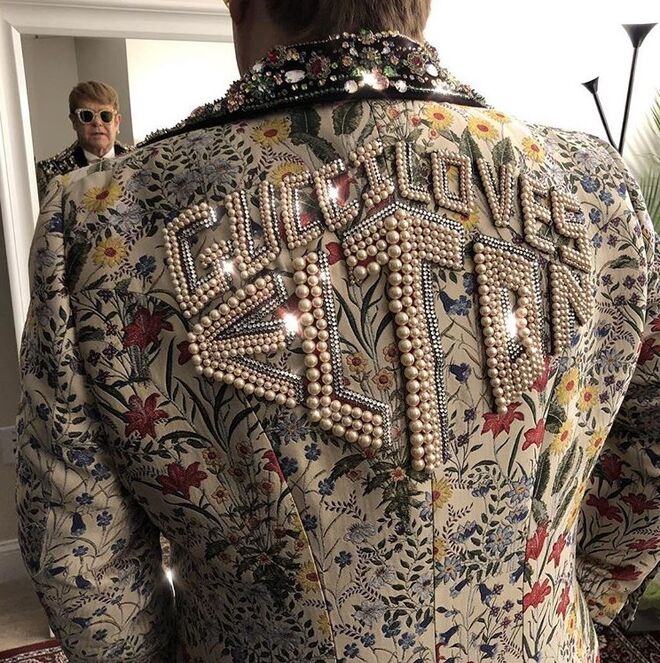 A capa de jacquard Gucci Flora personalizada, adornada com centenas de cristais, pérolas e a frase "Gucci loves Elton" incrustada nas costas