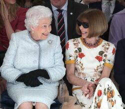 A rainha Isabel II assiste a um desfile de moda na primeira fila