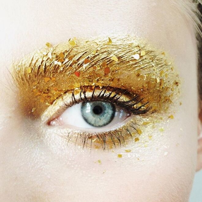 Olhos dourados com glitter até nas sobrancelhas para um efeito mais dramático.