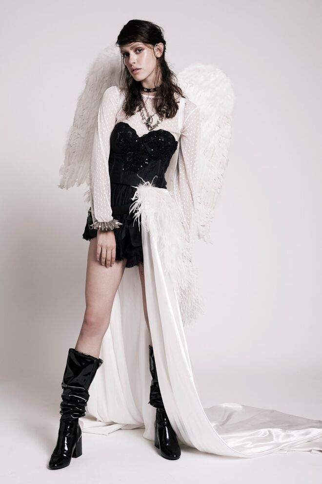 “The Bad Angel” |  Stylist: Nina Tamisa | Modelo: Catarina Silva – Face Models. Capa amarrada na cintura, Peris; vestido preto, Lia Rabello; camisola branca, botas e acessórios da produção; asas e pulseira da Peris.