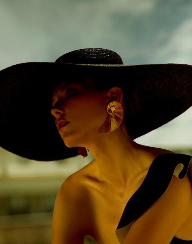 Fato de banho assimétrico em poliamida e elastano, Calzedonia. Chapéu em palha, Elisabetta Franchi. Brincos em prata com banho de ouro, Vanglória.