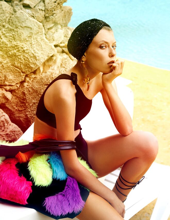 Fato de banho assimétrico em poliamida e elastano, Calzedonia. Turbante em tule e missangas, Carlos Gil. Brincos em metal dourado, Mango. Carteira em tela com aplicações em pelo, Jeremy Scott x Longchamp. Sandálias em pele sintética, Primark.