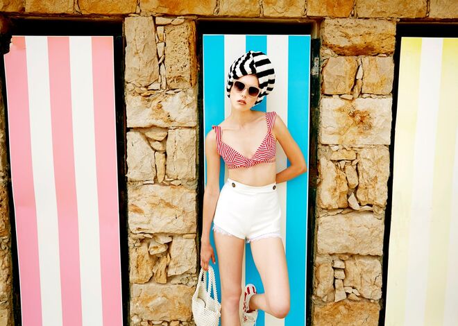 Biquíni em poliamida e elastano, Calzedonia. Calções em algodão e renda, Elisabetta Franchi. Ténis em lona, Converse. Vestido em malha, Mango (usado como turbante). Carteira em PVC, Mango. Óculos em massa, Primark.