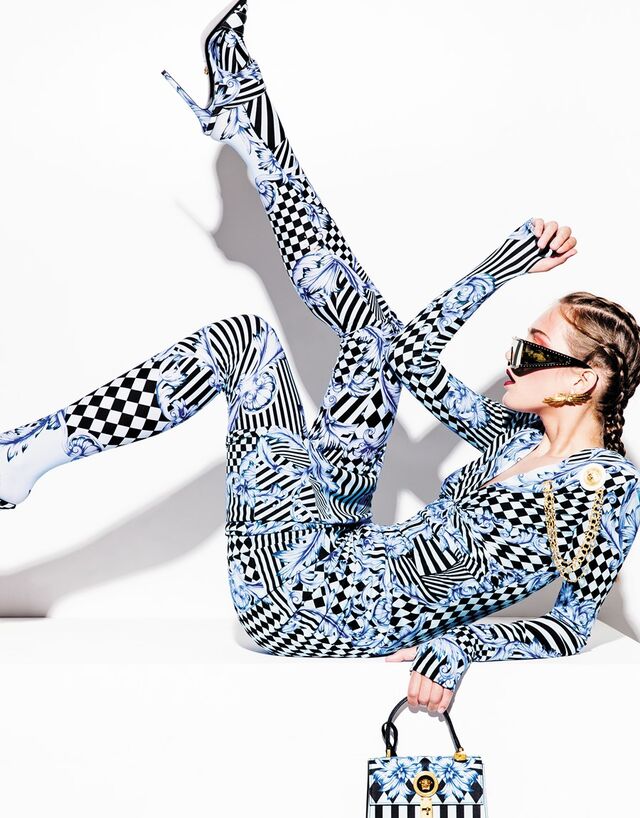 Vestido e leggings em viscose. Mules em algodão. Carteira em pele. Tudo Versace. Pregadeira em metal, Chanel. Óculos em acetato com tachas metálicas, Moschino. Brincos em latão com banho de ouro, Carolina Curado.