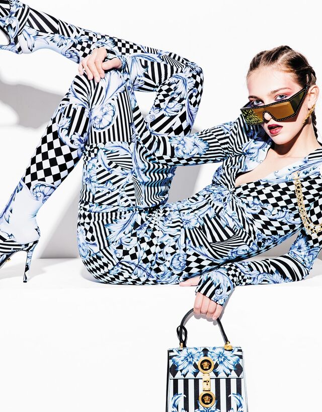 Vestido e leggings em viscose. Mules em algodão. Carteira em pele. Tudo Versace. Pregadeira em metal, Chanel. Óculos em acetato com tachas metálicas, Moschino. Brincos em latão com banho de ouro, Carolina Curado.