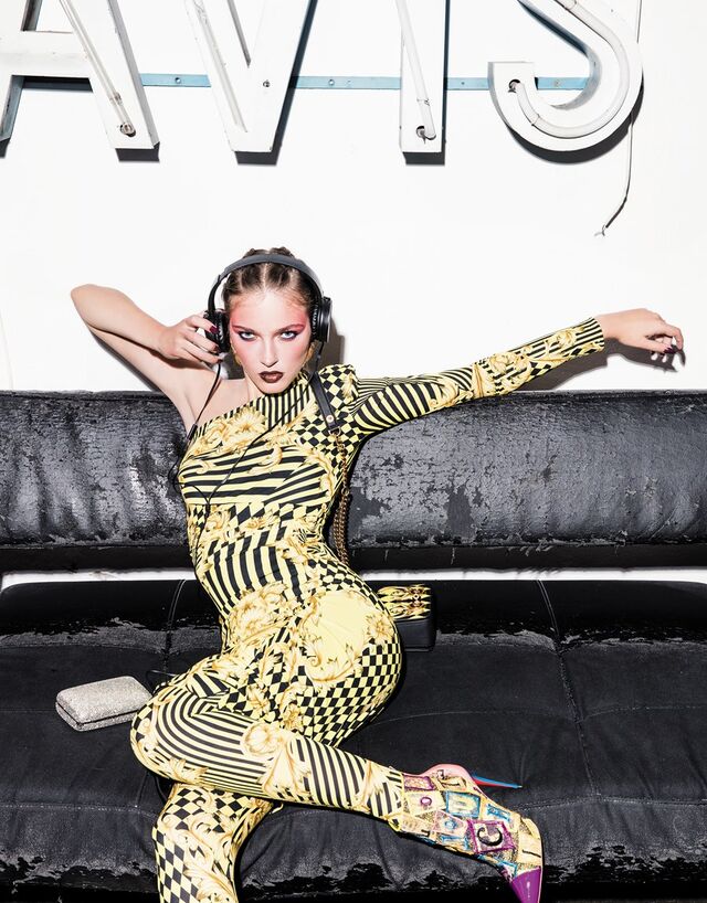 Vestido e leggings em viscose. Carteira em pele. Tudo Versace. Botins em pele e algodão, Christian Louboutin. Brincos em latão com banho de ouro, Carolina Curado. Clutch em metal e strass, Tous. Auscultadores da produção. 