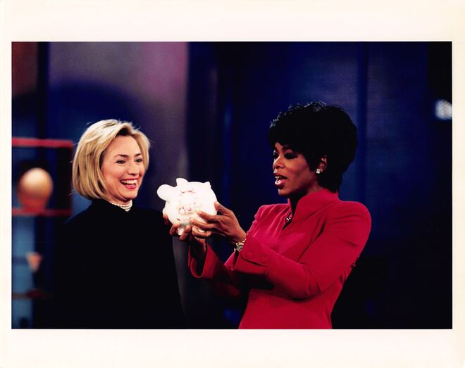 1997. A primeira dama Hillary Clinton dá à Oprah um porquinho mealheiro com trocos para a Oprah’s Angel Network, 