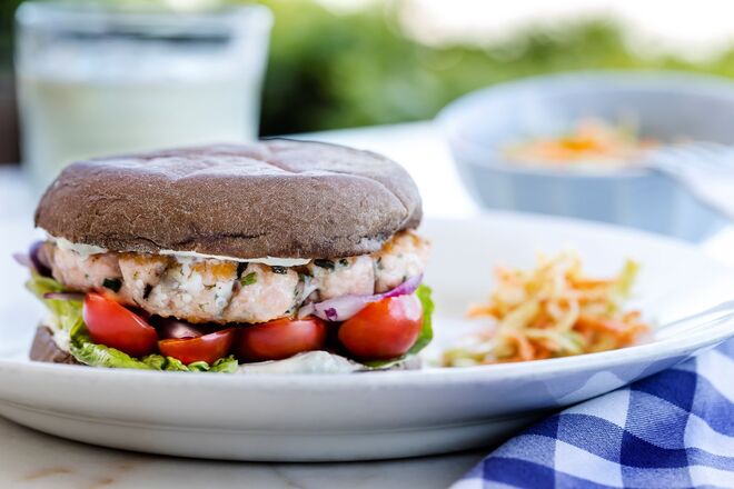 Beber um copo na esplanada do Cais da Pedra | Hamburguer Cais da Pedra com salmão, servido em bolo do caco de alfarroba com cebola roxa, alface, tomate cereja, molho de iogurte grego e cebolinho