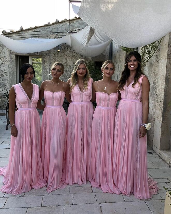 As damas de honor com vestidos longos plissados de georgette em tom rosa com incrustações de rendas, desenhados por Alberta Ferretti em colaboração com a Eco-Age