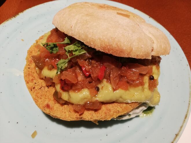 O Oriente Médio, hambúrguer veggie servido em pão pita com húmus, lima, paprika fumada, sésamo, molho Raita, abacate, coentros relish de tomate. 
