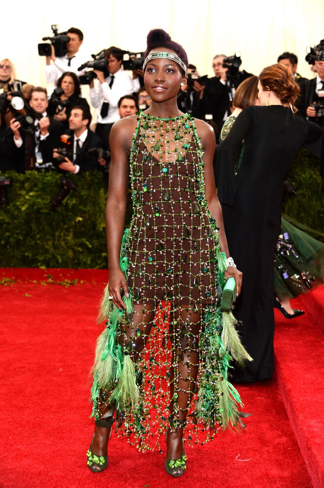 Lupita Nyong’o, 2014 | Neste ano e depois de vários looks fora da caixa, Lupita atraiu as atenções quando apareceu com uma criação da Prada em rede com detalhes em penas e jóias. 