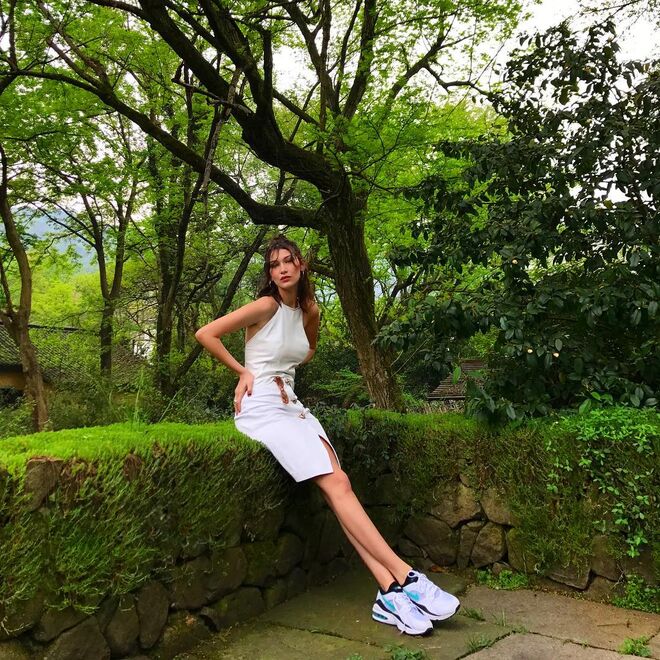 Bella Hadid destaca-se da sua paisagem como uma visão de branco, com os ténis chunky a completarem o look