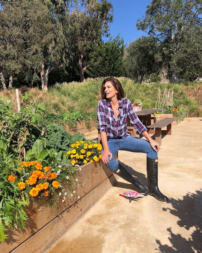 A ex-modelo Cindy Crawford usa as sua jeans num estilo agricoltora chic, com uma camisola de flanela e umas botas de cano alto