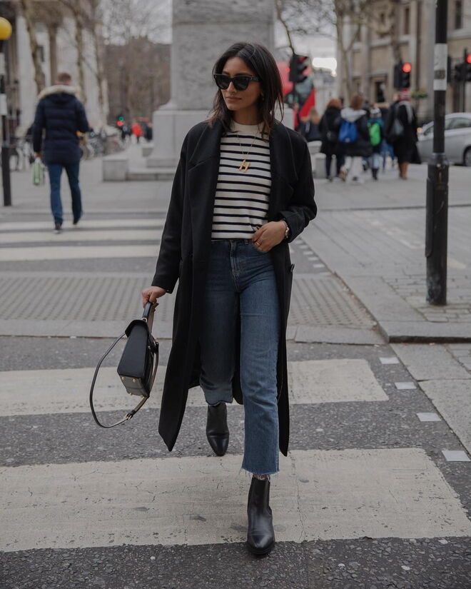 A influencer junta um casaco comprido e uns botins pretos, às suas calças que ficam em cima do tornozelo