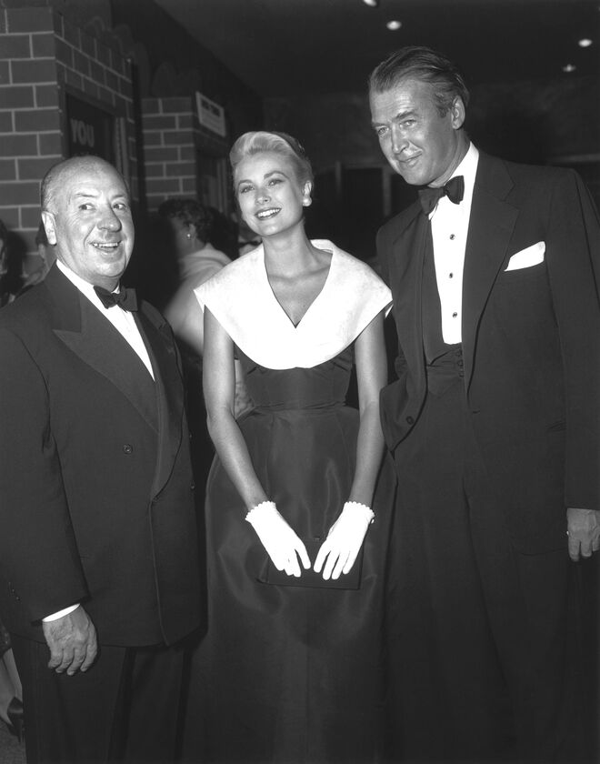 Grace Kelly com Alfred Hitchcock e James Stewart na estreia do file Janela Indiscreta, em 1954. Grace usa o vestido Caracas, Christian Dior – coleção New York, primavera/verão 1954.