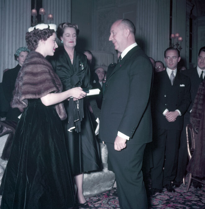 A princesa Margarida, com a duquesa de Marlborough, oferece a Christian Diorum pergaminho entitulando-o Honorary Life Membership of the British Red Cross, depois da apresentação da coleção de inverno do criador no palácio de Blenheim, a 3 de novembro de 1954. Exposição Christian Dior: Designer of Dreams no V&A de 2 de feveiro a 14 de julho de 2019.