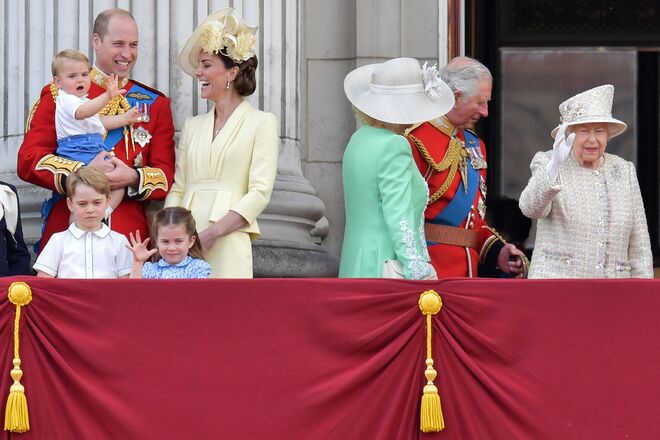 O príncipe William com o príncipe Louis ao colo, em pé os príncipes George e Charlotte, ao lado de Catherine, a duquesa de Cambridge, Camilla, a duquesa de Cornwall, o príncipe Carlos e a rainha Isabel II a acenar