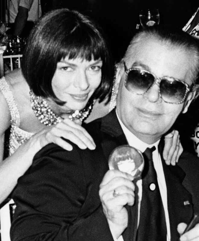Anna Wintour, diretora da Vogue Americana, com Lagerfeld, em 1980, quando o designer havia adotado óculos escuros e Mrs. Wintour ainda não os havia elegido como a sua imagem de marca.