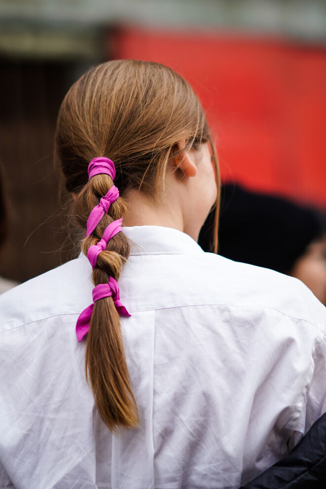 Uma convidada usa trança e cabelo amarrado com uma fita rosa, durante o London Fashion Week de fevereiro em 2019