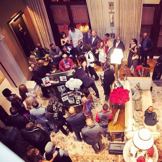 A sala de estar na mansão de Perry em Los Angeles, com janelas do chão ao teto, cortinados deslumbrantes e obras de arte nas paredes. | Na fotografia, Stevie Wonder está a tocar piano na festa de aniversário dos 45 anos de Tyler