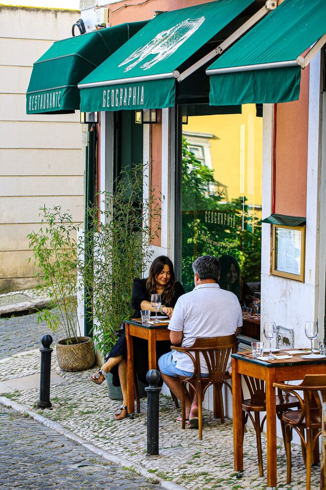 Geographia | Situado na esquina entre a rua do Conde e a rua do Olival, o Geographia arranjou espaço para uma pequena e convidativa esplanada. A acompanhar esta novidade, de segunda a sábado, das 19h às 20h, por cada bebida pedida o cliente terá direito a uma outra bebida (do mesmo valor) gratuita - é a Hora Feliz. 