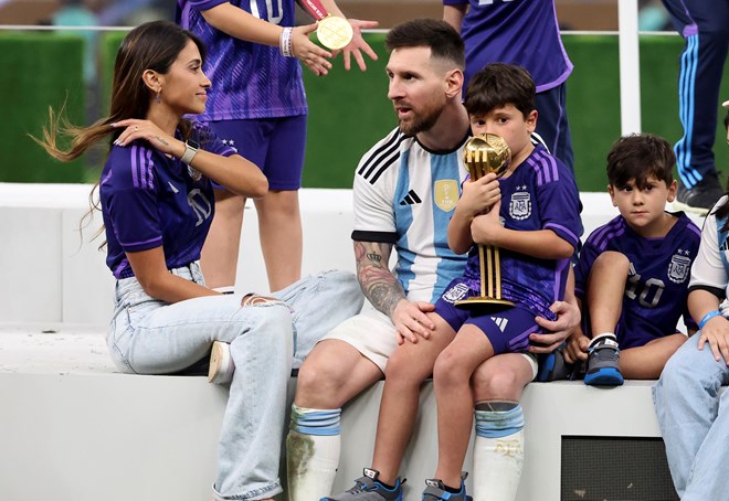 Messi con su familia - uno de los hijos besa el trofeo.