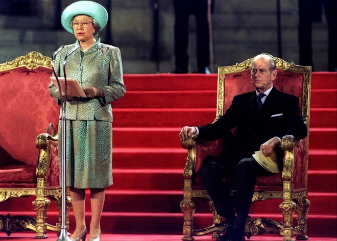 Rainha Isabel II a discursar e o príncipe Filipe a assistir.