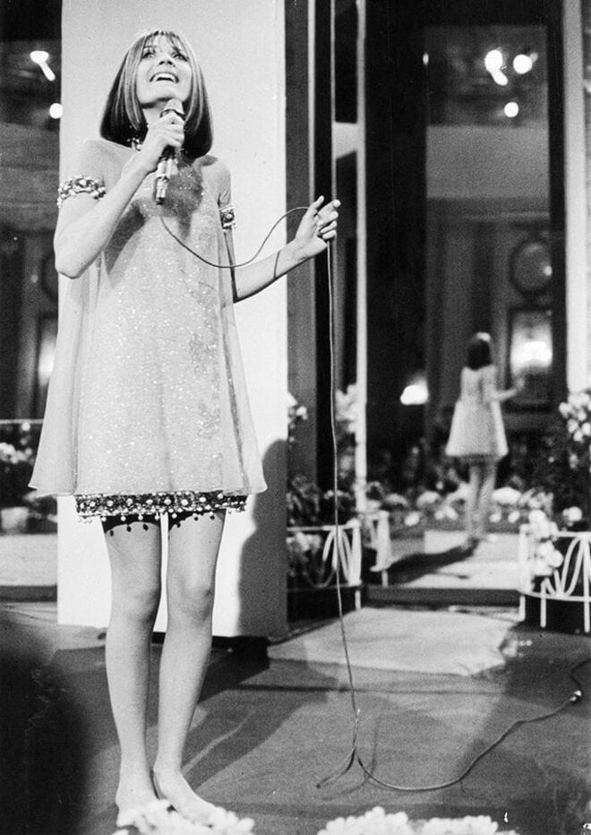 A representar o Reino Unido com uma simples cantiga pop "Puppet on a String", usou um minivestido de joias preciosas muito ao estilo 'swinging sixties', com chiffon sobre apliques. 