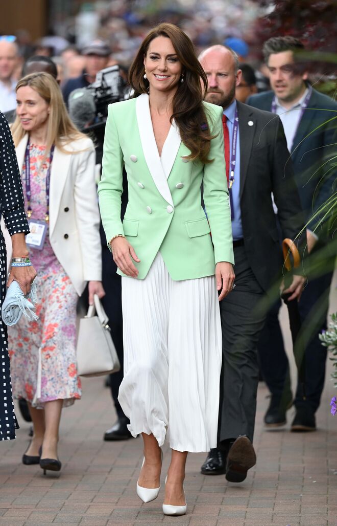 Num blazer verde menta da Balmain, com saia midi branca plissada e sapatos brancos Gianvito Rossi. 