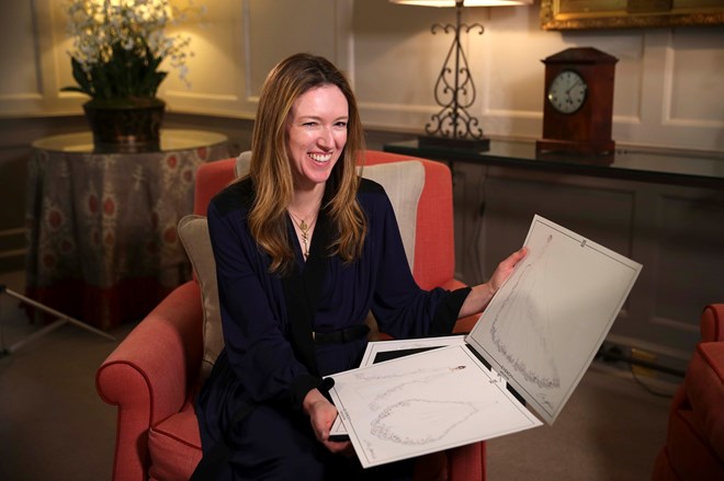 Clare Waight Keller com o design original do vestido de noiva de Meghan Markle nas mãos.