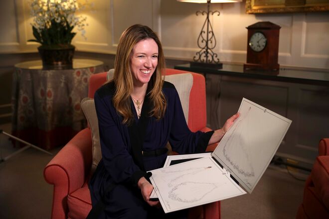 Clare Waight Keller com o design original do vestido de noiva de Meghan Markle nas mãos.
