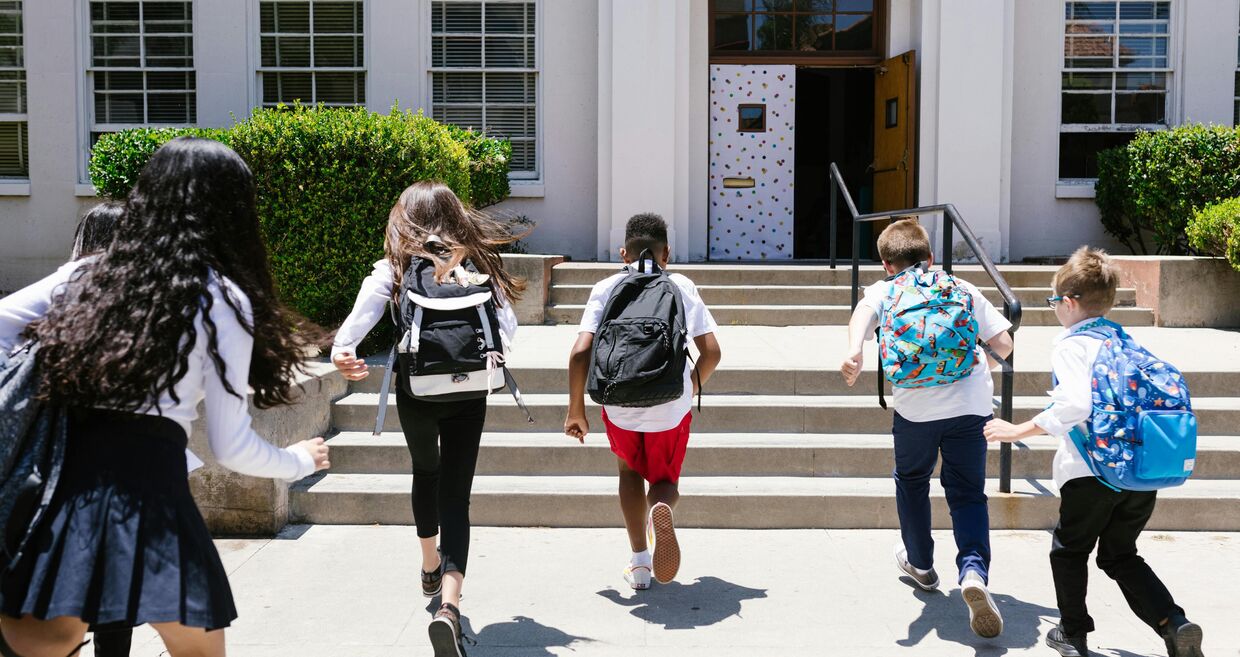 Alunos caminham para a escola num dia ensolarado