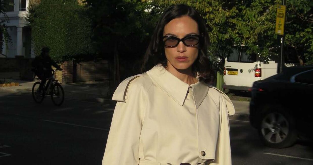 Modelo usa trench coat e óculos de sol na rua