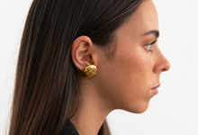 Mulher com brincos dourados e blazer riscado da coleção Seaside outono/inverno 2025