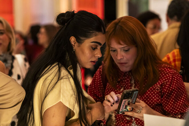 Convidados consultam telemóvel na festa de aniversário da revista Máxima.