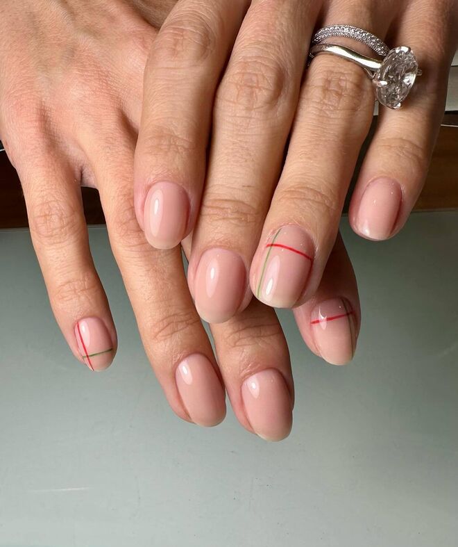 Para quem gosta de detalhes discretos mas com um toque natalício, esta manicure combina uma base nude com linhas finas em vermelho e verde.