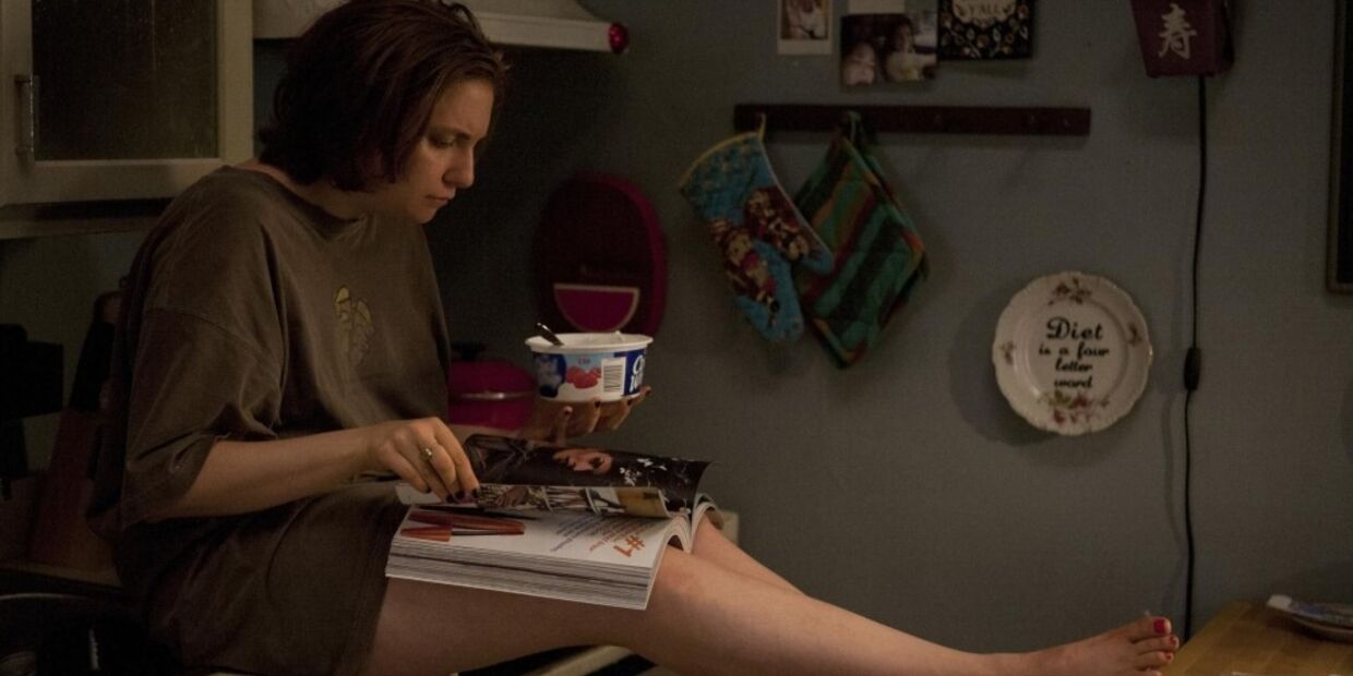 Mulher lê revista enquanto come iogurte