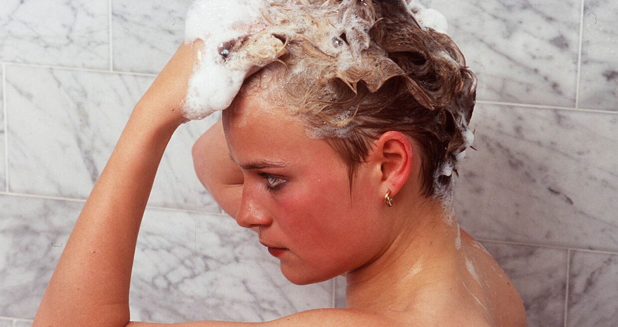 Uma mulher lava o cabelo com champô para evitar a queda de cabelo